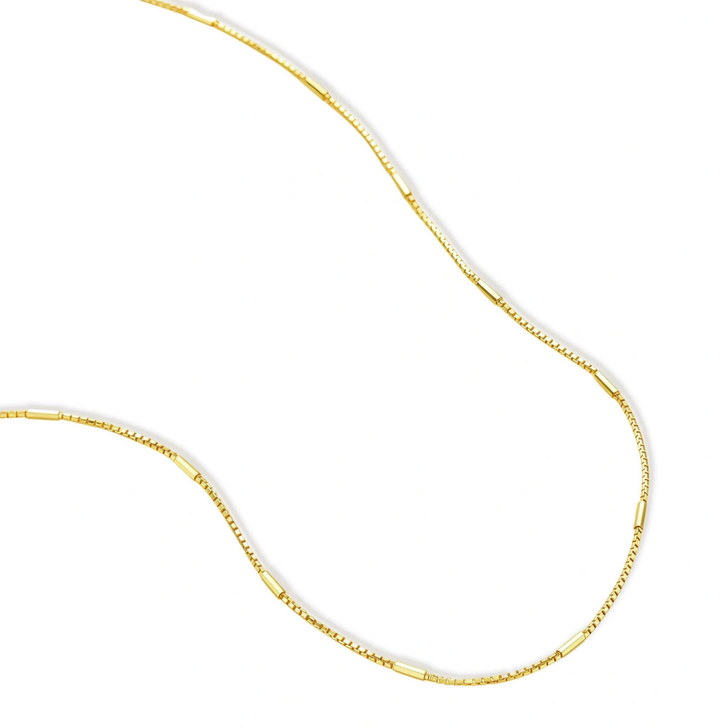 Delicate gold-plated sterling silver chain necklace with geometric segments displayed against cream background