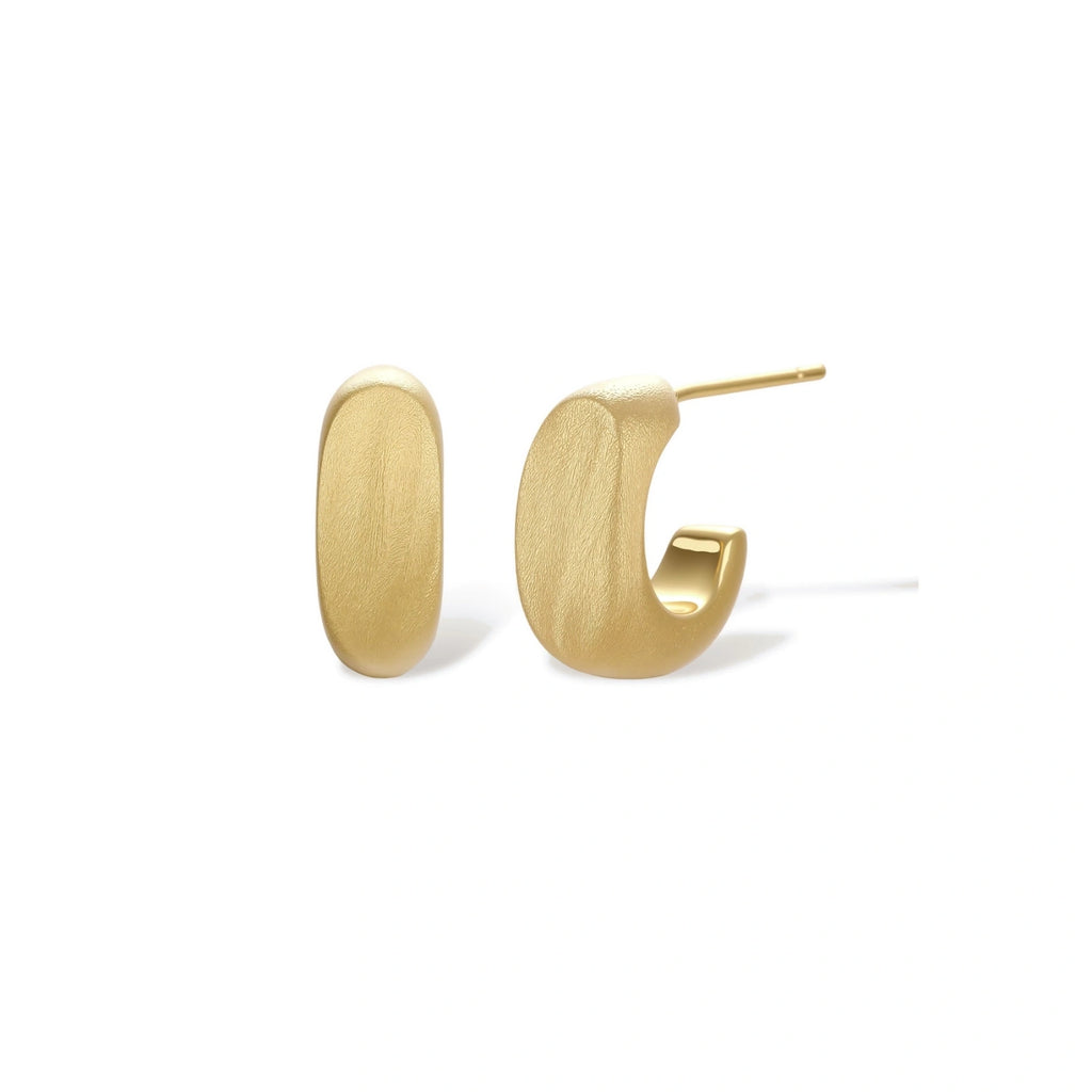 Small gold huggie earrings with matte finish, 14mm diameter, shown against cream background for everyday elegance.