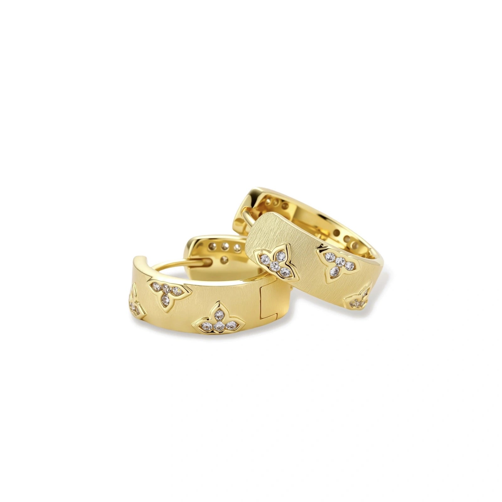 Gold-plated hoop earrings with textured surface and raised floral motifs set with clear zirconia stones on cream background.