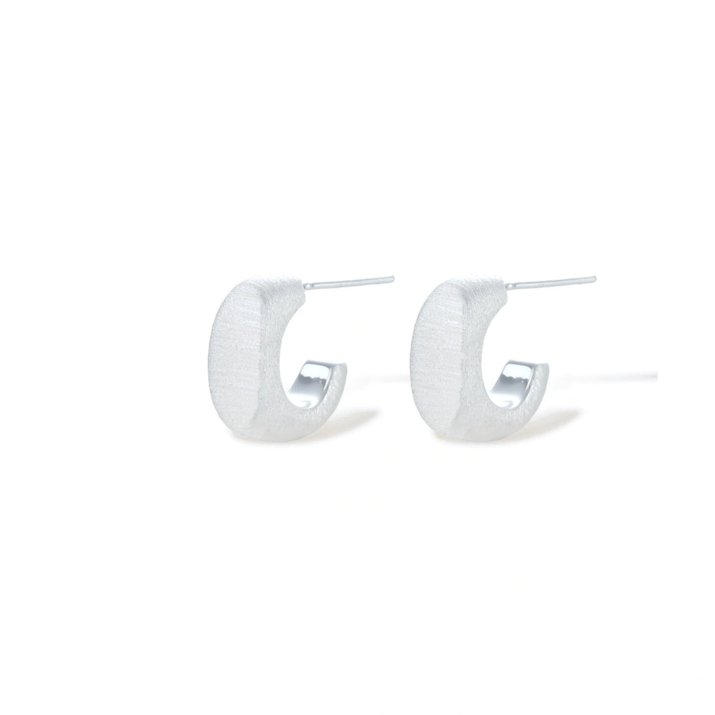 Pair of small silver-plated huggie hoop earrings with clean minimal design on neutral background.
